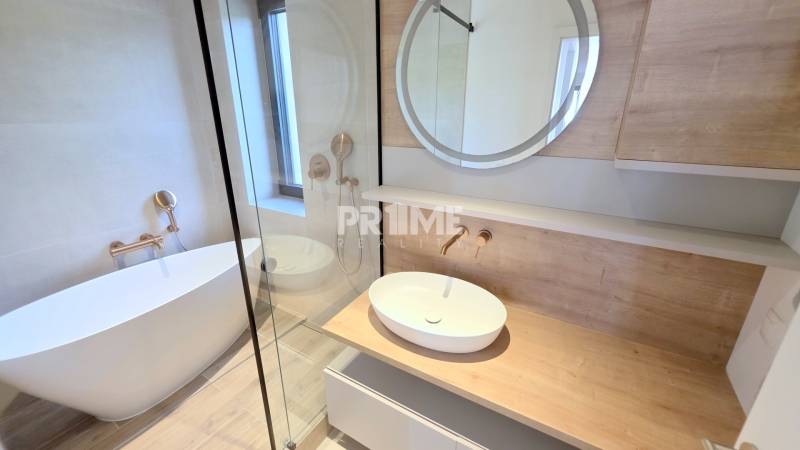 LUXUSNÝ 3i byt,PARKING,CHLADENIE,TERASA,Grand Koliba, Frankovská ulica - Elegantná kúpeľňa s voľne stojacou vaňou v 3-izbovom byte, drevené povrchy, okno.