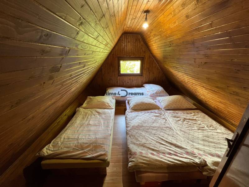 NA PREDAJ Chata na Duchonke- Prašice - Podkrovná izba na chate s drevenými stenami a dvoma posteľami.