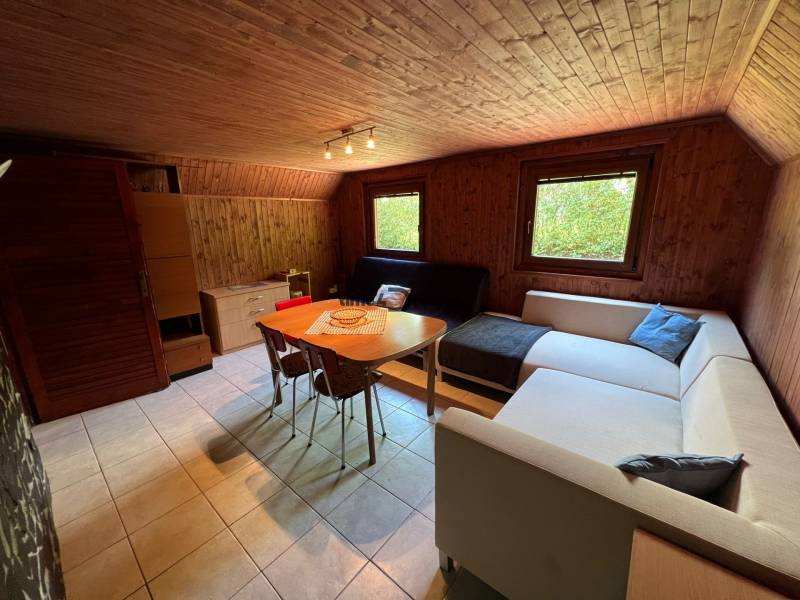 NA PREDAJ Chata na Duchonke- Prašice - Interiér chaty so sedačkou, jedálenským stolom a drevenými stenami.