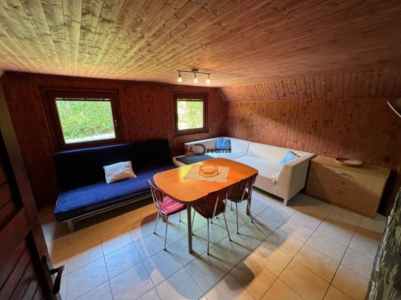 NA PREDAJ Chata na Duchonke- Prašice - Izba v chate s dreveným obkladom, sedačkou a stolom s jedálenskými stoličkami.