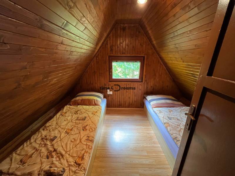 NA PREDAJ Chata na Duchonke- Prašice - Drevený interiér chaty s dvoma postelemi a podlahou s dreveným dekorom.