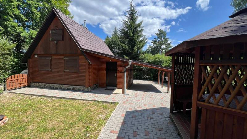 NA PREDAJ Chata na Duchonke- Prašice - Drevená chata v Prašiciach s altánkom, stromami a vydláždeným prístupom.