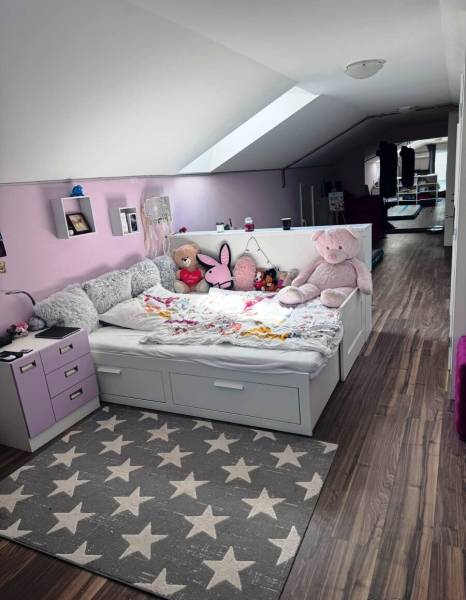 Priestranný 5-izbový rodinný dom s pohodlným dojazdom do Bratislavy  - Detská izba v rodinnom dome s posteľou, plyšovými hračkami a podlahou s dreveným dekorom.