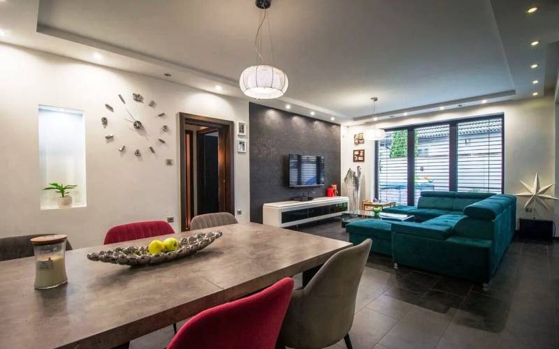 Priestranný 5-izbový rodinný dom s pohodlným dojazdom do Bratislavy  - Obývačka rodinného domu s komfortnou sedačkou, stolíkom a televízorom, veľké okná vpúšťajú svetlo.