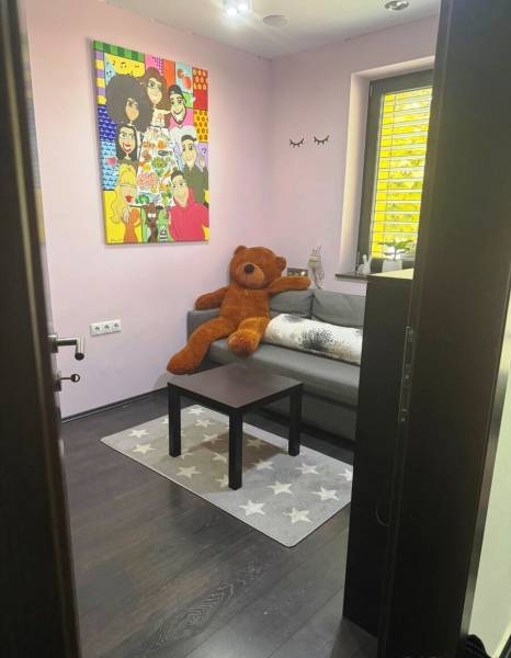 Priestranný 5-izbový rodinný dom s pohodlným dojazdom do Bratislavy  - Izba v rodinnom dome s farebným obrazom, gaučom a veľkým plyšovým medveďom.