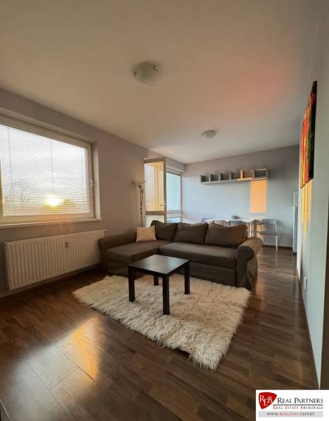 Prenájom 2-izb byt v uzavretom areáli Bratislava II - Obývacia izba v 2-izbovom byte s pohovkou, konferenčným stolíkom a podlahou s dreveným dekorom.