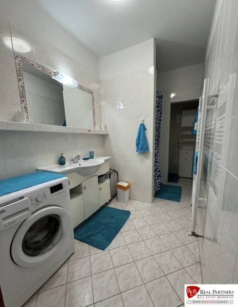 Prenájom 2-izb byt v uzavretom areáli Bratislava II - Kúpeľňa v 2-izbovom byte s práčkou, bielymi kachličkami a modrými doplnkami.