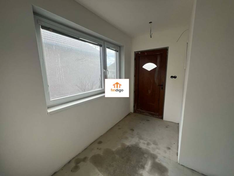 PREDAJ - 3-izbový rodinný dom po kompletnej interiérovej rekonštrukcii - Chodba v rodinnom dome s betónovou podlahou, drevenými dverami a plastovým oknom.