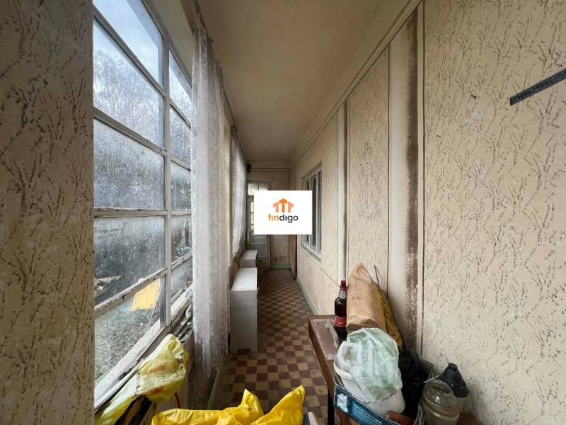 PREDAJ - Rodinný dom na rekonštrukciu s veľkým pozemkom – Kuraľany - Zasklená chodba v rodinnom dome s výhľadom a odloženými predmetmi na podlahe.