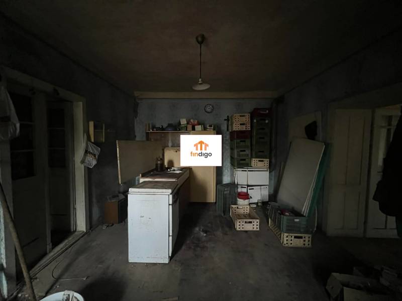 PREDAJ - Rodinný dom na rekonštrukciu s veľkým pozemkom – Kuraľany - Interiér rodinného domu s jednoduchou kuchyňou a podlahou s dreveným dekorom.