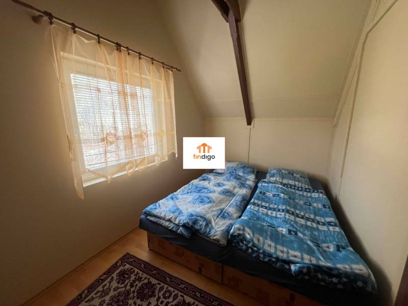 PREDAJ - Zrekonštruovaná rekreačná chata - Chľaba - Spálňa na chate s dvojlôžkom, bielymi stenami a podlahou s dreveným dekorom.