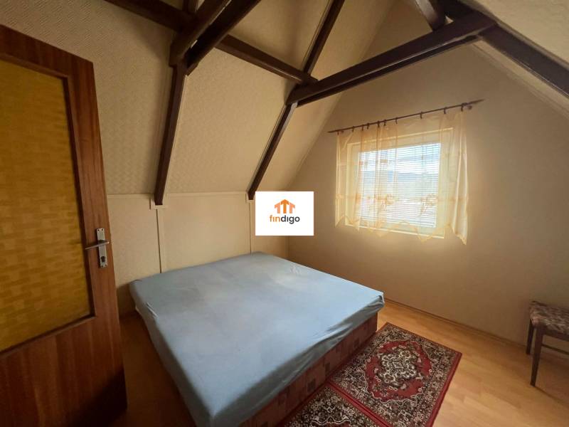 PREDAJ - Zrekonštruovaná rekreačná chata - Chľaba - Spálňa s dreveným dekórom, strešné trámy, jednoduché zariadenie, posteľ, koberček, záclona.