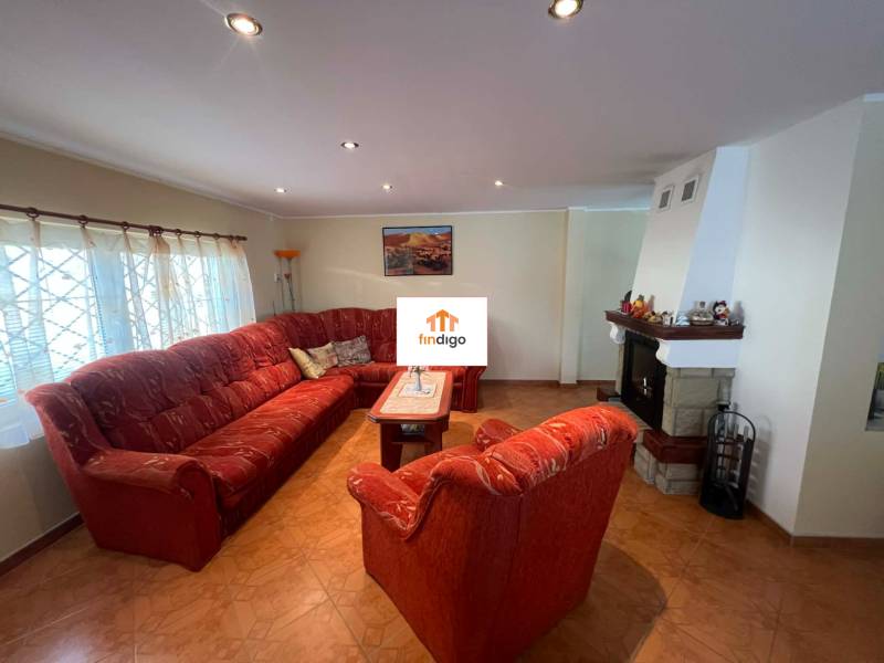 PREDAJ - Zrekonštruovaná rekreačná chata - Chľaba - Obývacia izba s krbom, červeným gaučom a podlahou s dreveným dekorom v chate.