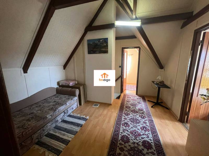 PREDAJ - Zrekonštruovaná rekreačná chata - Chľaba - Strešná izba Chaty s podlahou s dreveným dekorom, gaučom, kobercom a stolíkom.