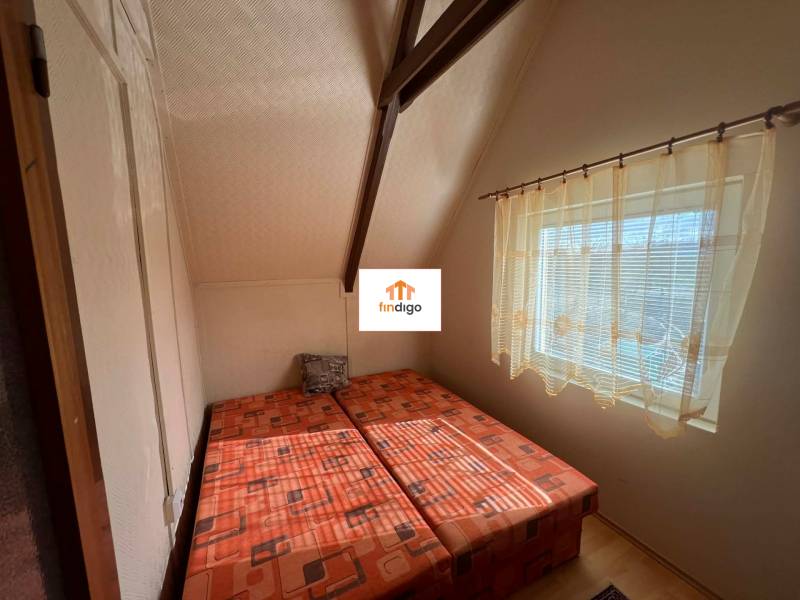 PREDAJ - Zrekonštruovaná rekreačná chata - Chľaba - Spálňa v chate s dvoma posteľami a veľkým oknom, závesy prepúšťajú svetlo.