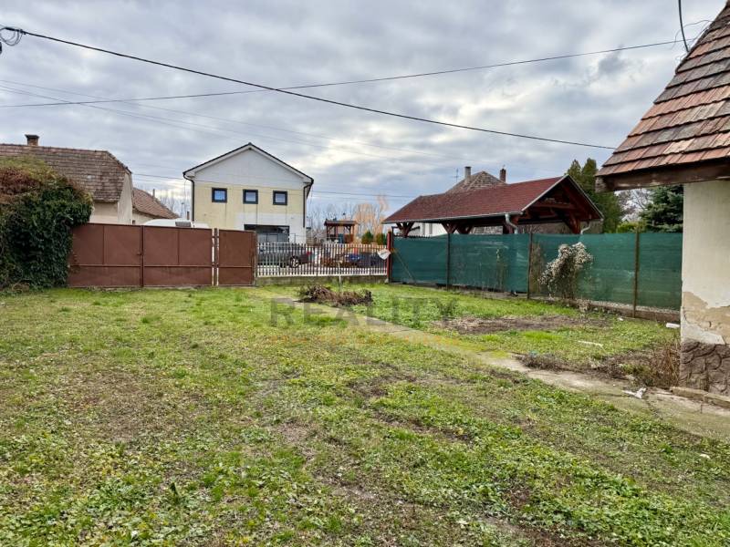 Na predaj pozemok 1065 m2, obec Dobrohošť v blízkosti Bratislavy - Pozemok na bývanie v Dobrohošti na Dobrohošť ulici s trávnatou plochou a bránou.