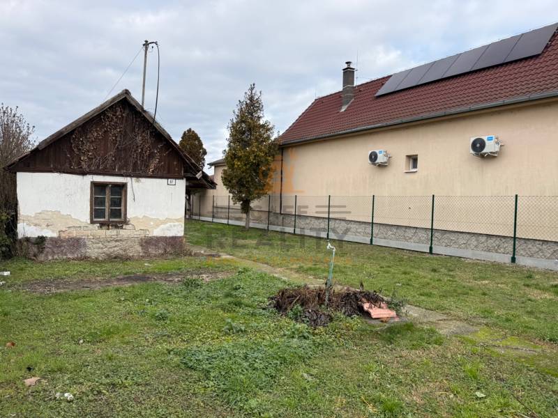 Na predaj pozemok 1065 m2, obec Dobrohošť v blízkosti Bratislavy - Pozemok na bývanie v Dobrohošti. Stará stavba vedľa modernejšieho domu so solárnymi panelmi.