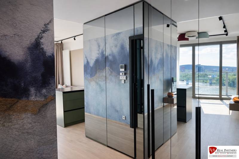 Prenájom 2-izbový byt s loggiou,55m2, EUROVEA TOWER - 2-izbový byt s farebnou umeleckou stenou, podlaha s dreveným dekorom a veľké okno.