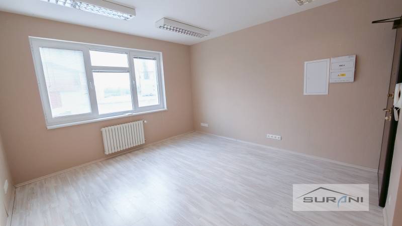  	 Bez Provízie | Kancelária 17m2 | Paulínyho ulica | Bratislava - Kancelária s veľkým oknom, podlahou s dreveným dekorom a radiátorom.