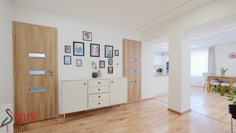 TOP - Rodinný dom s veľkým pozemkom - Dolný Hričov - Interiér rodinného domu s podlahou s dreveným dekorom, bielym nábytkom a dekoráciami.