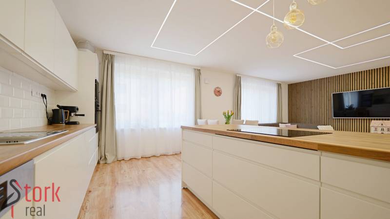 TOP - Rodinný dom s veľkým pozemkom - Dolný Hričov - Kuchyňa v Rodinnom dome s podlahou s dreveným dekorom, svetlým nábytkom a veľkým oknom.