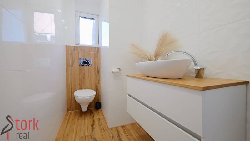 TOP - Rodinný dom s veľkým pozemkom - Dolný Hričov - Kúpeľňa s umývadlom na komode a podlahou s dreveným dekorom.