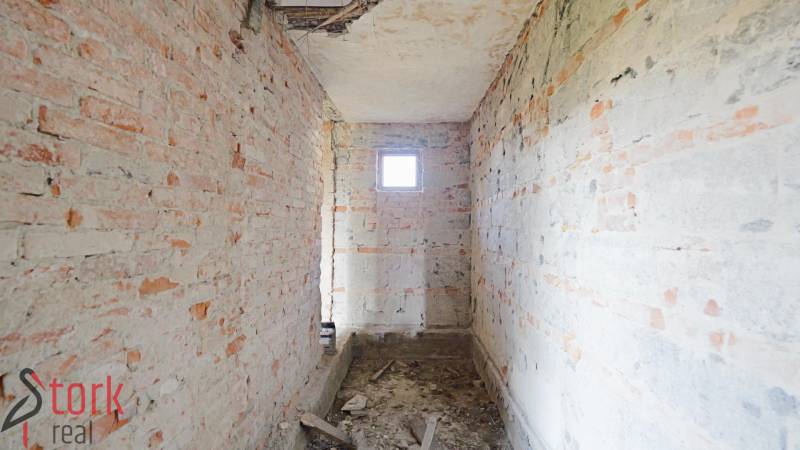 TOP - Rodinný dom s veľkým pozemkom - Dolný Hričov - Nedokončená miestnosť s holými tehlovými stenami v rodinnom dome.