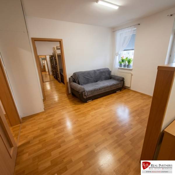 Na prenájom pekný 2-izbový byt s loggiou, Most pri BA - Izba s rozkladacou sedačkou, oknom a podlahou s dreveným dekorom v 2-izbovom byte.