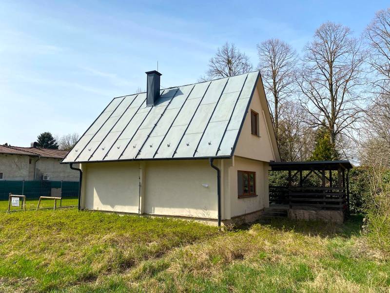 Zrekonštruovaná rekreačná chata v Jahodnej (Dunajské Mlyny) - Chata v Jahodnej s plechovou strechou, obklopená trávnatým porastom a stromami.