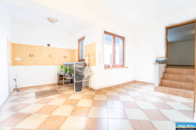 RD PO REKONŠTRUKCII spolu so STAVEBNÝM POZEMKOM na druhý dom - takmer  - Interiér rodinného domu s dlažbou a kuchynským kútom.