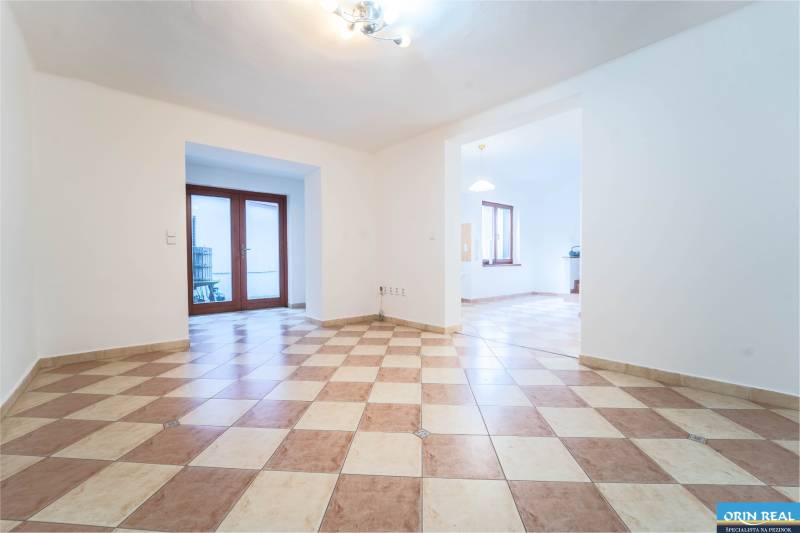 RD PO REKONŠTRUKCII spolu so STAVEBNÝM POZEMKOM na druhý dom - takmer  - Priestranná miestnosť v rodinnom dome s kachličkovou podlahou a drevenými dverami na terasu.