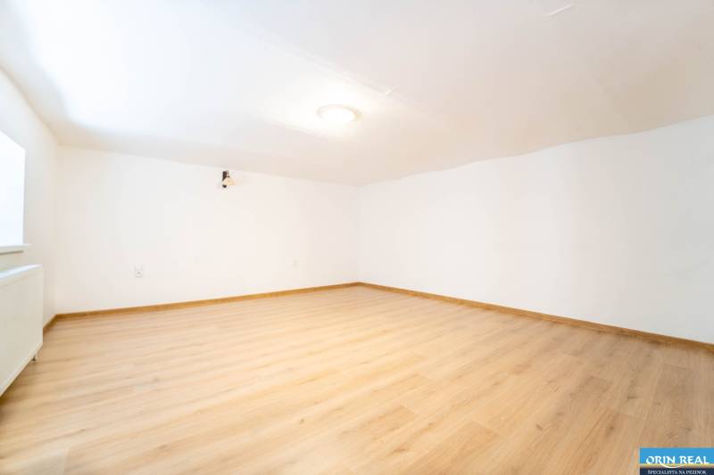 RD PO REKONŠTRUKCII spolu so STAVEBNÝM POZEMKOM na druhý dom - takmer  - Priestranná miestnosť v rodinnom dome s bielymi stenami a podlahou s dreveným dekorom.