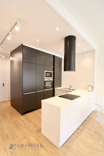 Komfortne vybavený 2-izbový byt v projekte 2 Sýpky - Kuchyňa v 2-izbovom byte s priestrannou kuchynskou linkou a podlahou s dreveným dekorom.