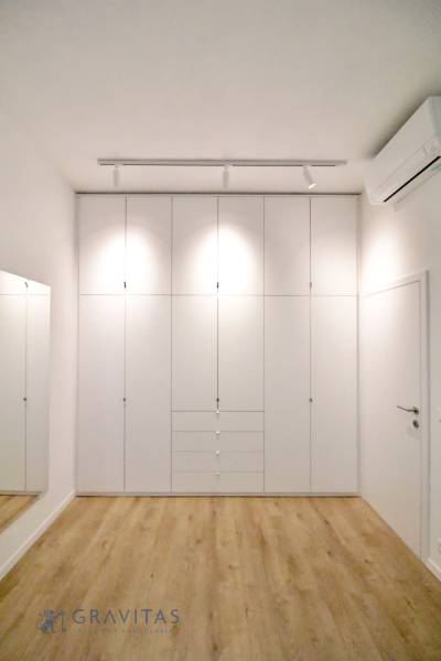 Komfortne vybavený 2-izbový byt v projekte 2 Sýpky - Spálňa s bielou vstavanou skriňou a podlahou s dreveným dekorom v 2-izbovom byte.