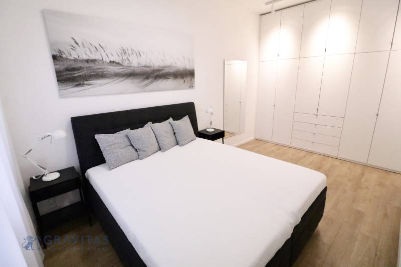 Komfortne vybavený 2-izbový byt v projekte 2 Sýpky - Spálňa v 2-izbovom byte s bielymi skriňami a podlahou s dreveným dekorom.