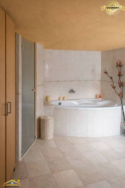 Čadca-Horelica | samostatná stavba s wellness zónou, sauna, krb - Kúpeľňa v rodinnom dome s rohovou vaňou, dekoratívnymi kvetinami a béžovými dlaždicami.