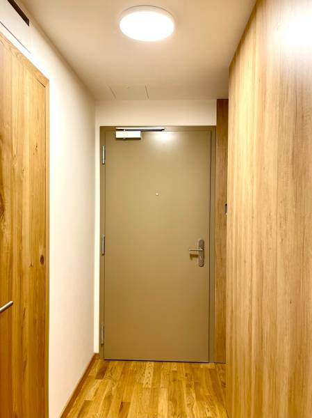 I 3 i byt s parkovaním v rezidenčnom komplexe METROPOLIS - Interiér 3-izbového bytu s podlahou s dreveným dekorom a bezpečnostnými dverami.