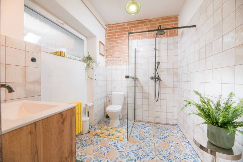 Na predaj zrekonštruovaný dom na Štefánikovej ulici, Trenčín - Kúpeľňa v rodinnom dome s farebnými dlaždicami, sprchovým kútom a rastlinou.