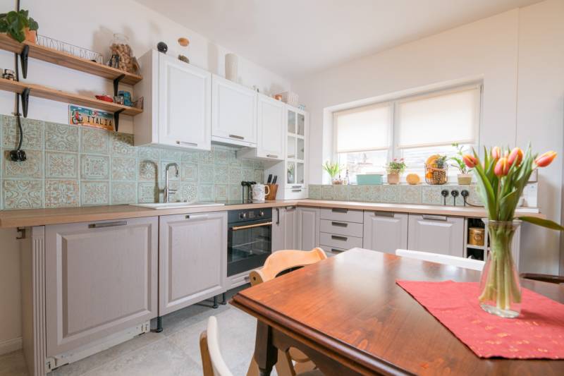 Na predaj zrekonštruovaný dom na Štefánikovej ulici, Trenčín - Rodinný dom: Kuchyňa s kvetinovou výzdobou a dekoratívnymi obkladačkami na stene.