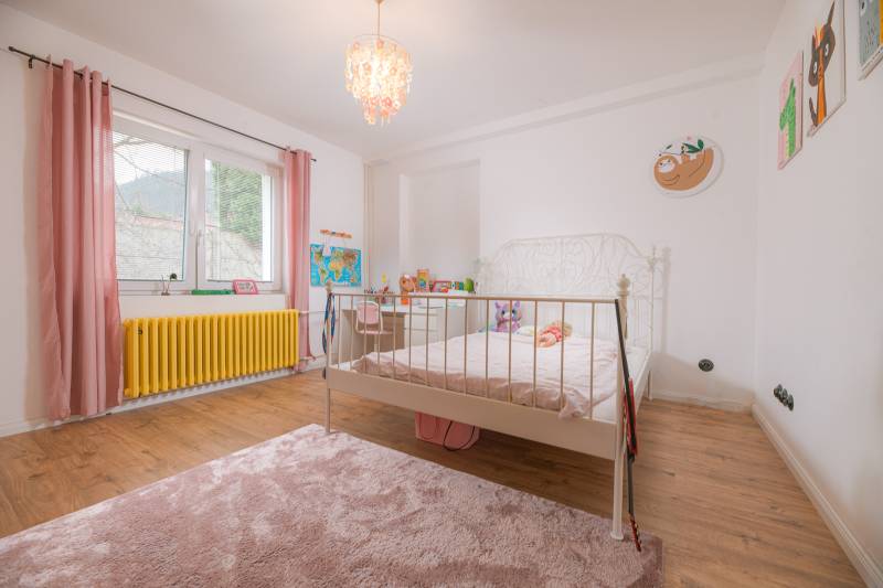 Na predaj zrekonštruovaný dom na Štefánikovej ulici, Trenčín - Detská izba v rodinnom dome s podlahou s dreveným dekorom a ružovými doplnkami.