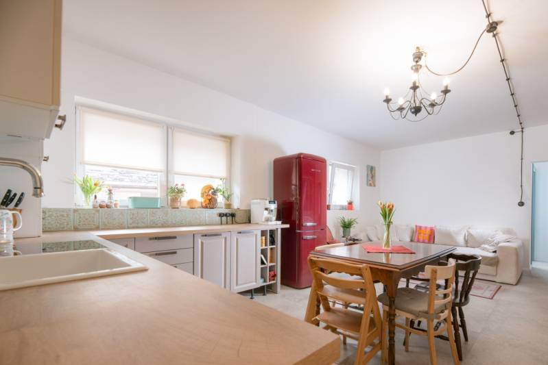 Na predaj zrekonštruovaný dom na Štefánikovej ulici, Trenčín - Kuchyňa v rodinnom dome s červenou chladničkou, dreveným stolom a pohovkou.