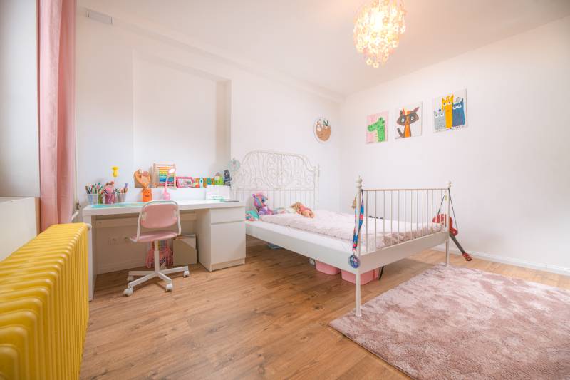 Na predaj zrekonštruovaný dom na Štefánikovej ulici, Trenčín - Detská izba v rodinnom dome s podlahou s dreveným dekorom a svetlým nábytkom.