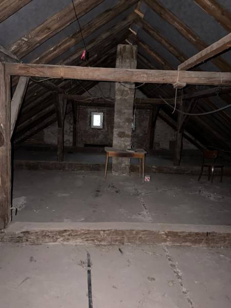 Na predaj zrekonštruovaný dom na Štefánikovej ulici, Trenčín - Podkrovie v rodinnom dome so surovými drevenými trámami a úložným stolom.