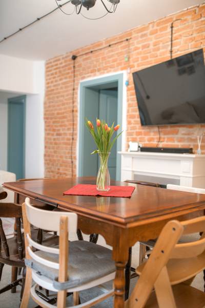 Na predaj zrekonštruovaný dom na Štefánikovej ulici, Trenčín - Jedálenský stôl s vázou tulipánov, tehla, TV na stene v rodinnom dome.