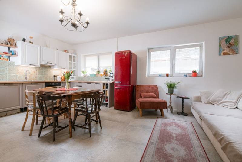 Na predaj zrekonštruovaný dom na Štefánikovej ulici, Trenčín - Kuchyňa v rodinnom dome s bielymi skrinkami, červenou chladničkou a dreveným stolom.