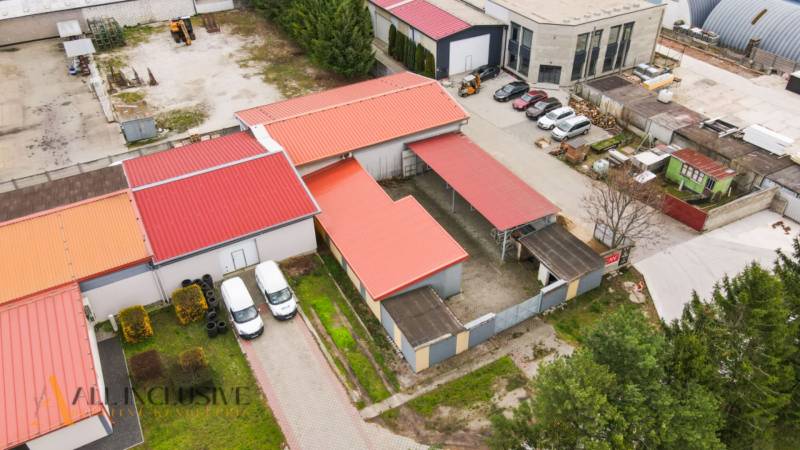 PRAKTICKÉ SKLADOVÉ PRIESTORY  | DOPRAVNÁ | TOPOĽČANY - Priemyselný areál na ulici s halami a skladmi, autá zaparkované v blízkosti budov.