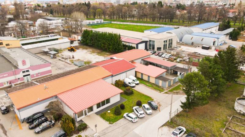 PRAKTICKÉ SKLADOVÉ PRIESTORY  | DOPRAVNÁ | TOPOĽČANY - Oblasť plná budov so skladmi a halami na ulici Dopravná, obklopená zeleňou a parkovaním.