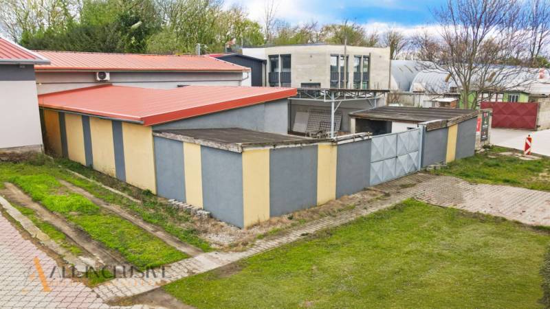 PRAKTICKÉ SKLADOVÉ PRIESTORY  | DOPRAVNÁ | TOPOĽČANY - Budovy na ulici Dopravná s červenými strechami, skladové haly obklopené zeleňou a stromami.