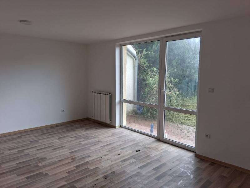 PREDAJ – 4-izbový rodinný dom v radovej zástavbe s garážou - Izba s podlahou s dreveným dekorom v rodinnom dome a výhľadom do záhrady.