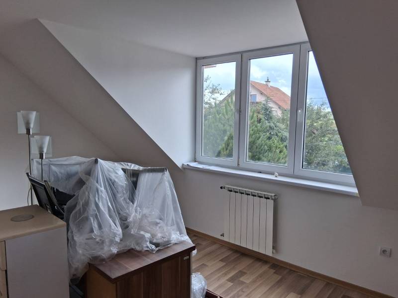 PREDAJ – 4-izbový rodinný dom v radovej zástavbe s garážou - Podkrovná izba s veľkým oknom, radiátorom a podlahou s dreveným dekorom.